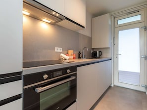 A modern kitchen with a built-in oven, a coffee maker, and a roll of paper towels on the counter. - Apartment in Zoutelande Near Sunny Beach (Zoutelande)