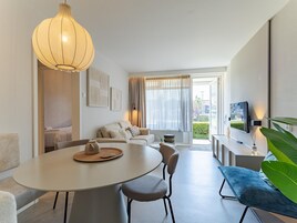 Un salon moderne comprenant un coin repas, un canapé, un téléviseur et une grande plante.