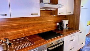 A modern kitchen with wooden countertops, stainless steel appliances, and white cabinetry. - Spacious Apartment in Gortipohl With Garden (Sankt Gallenkirch)