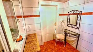 A bathroom with white tiled walls, a wooden ceiling, a white toilet, a small vanity with a mirror, and a wicker shelf. - Spacious Apartment in Gortipohl With Garden (Sankt Gallenkirch)