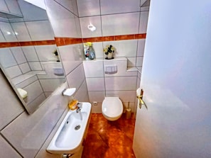 A bathroom with a sink, toilet, and storage cabinet.