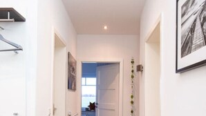A hallway with a wooden bench, a radiator, and a door leading to a room with a window. - Ostfriesland to Huus (Hinte)