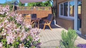 A patio with a table and chairs, a wooden fence, and a house with a window. - Ostfriesland to Huus (Hinte)