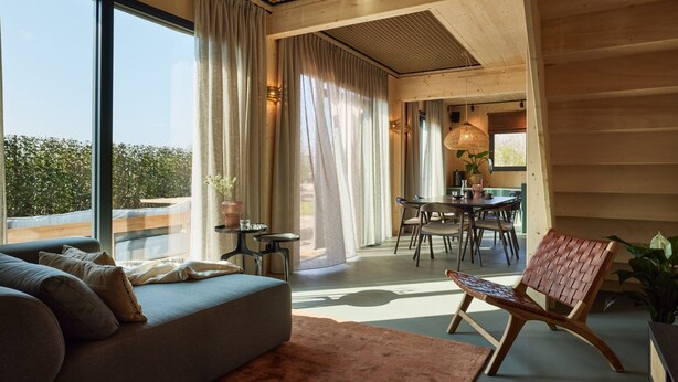A modern interior with a sofa, dining table, and chairs. - Holiday Home in Drents-friese Wold With Sauna (Appelscha)