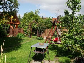 A rustic outdoor setting with a swing set, a wooden table, and a fenced garden area. - Harz Enjoyment Modern Retreat (Wernigerode)