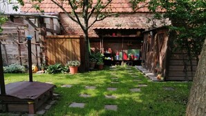 A backyard with a stone pathway leading to a wooden deck, surrounded by potted plants and a brick wall. - Harz Enjoyment Modern Retreat (Wernigerode)