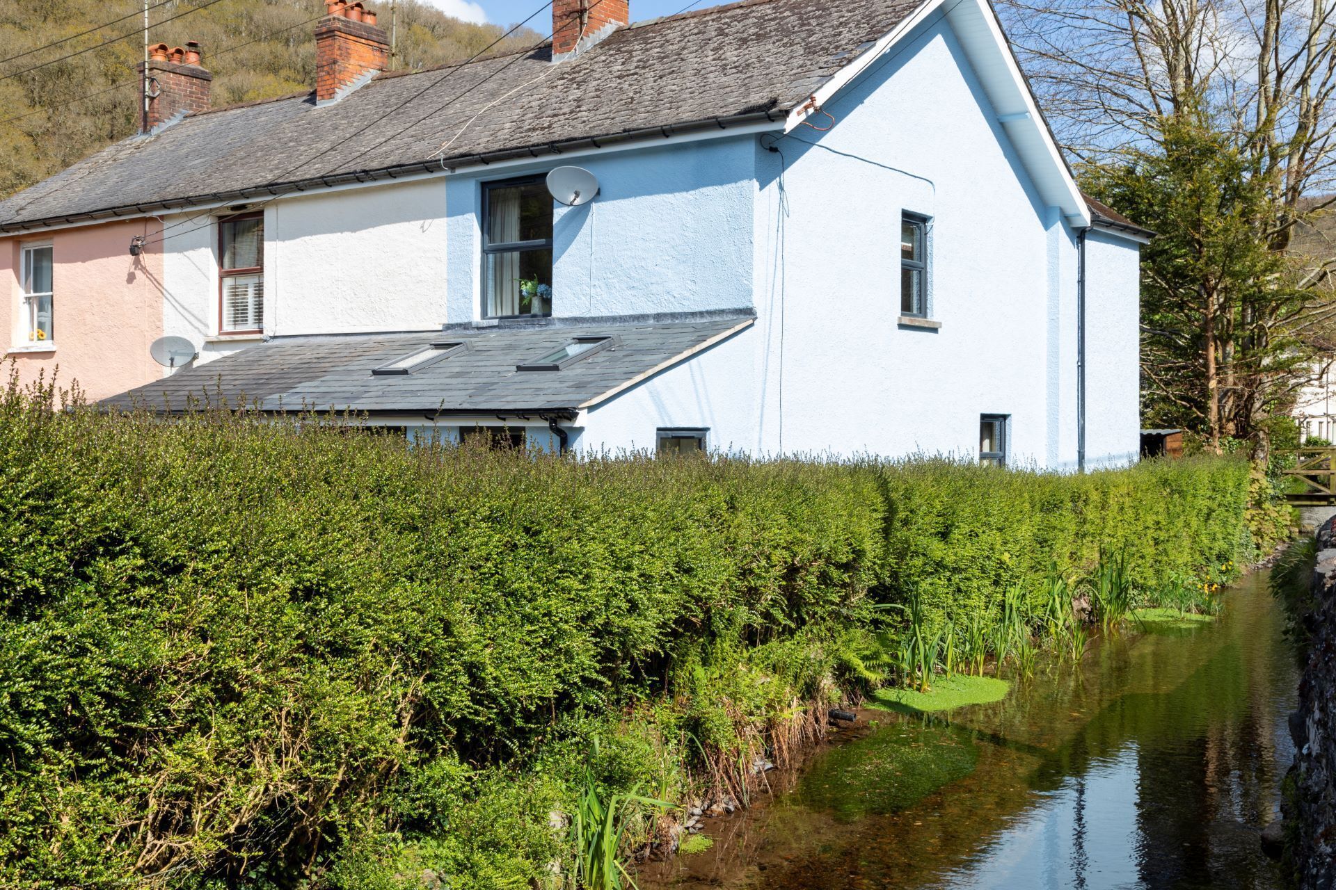 Une maison à deux étages, dotée d’un toit en pente, d’une antenne parabolique et d’une petite fenêtre.