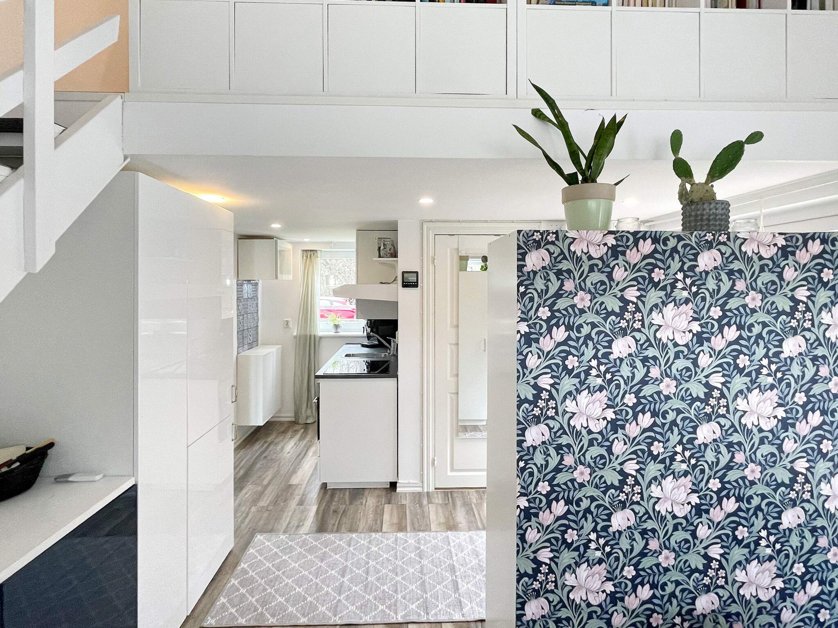 A modern kitchen with white cabinetry, a patterned backsplash, and a small potted plant on the counter.
