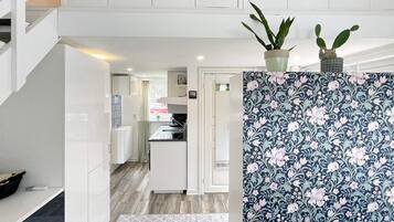 A modern kitchen with white cabinetry, a patterned backsplash, and a small potted plant on the counter.