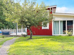A modern building with a red exterior and large windows, surrounded by a well-maintained lawn and a tree. - 4 Star Holiday Home in Rockneby (Rockneby)