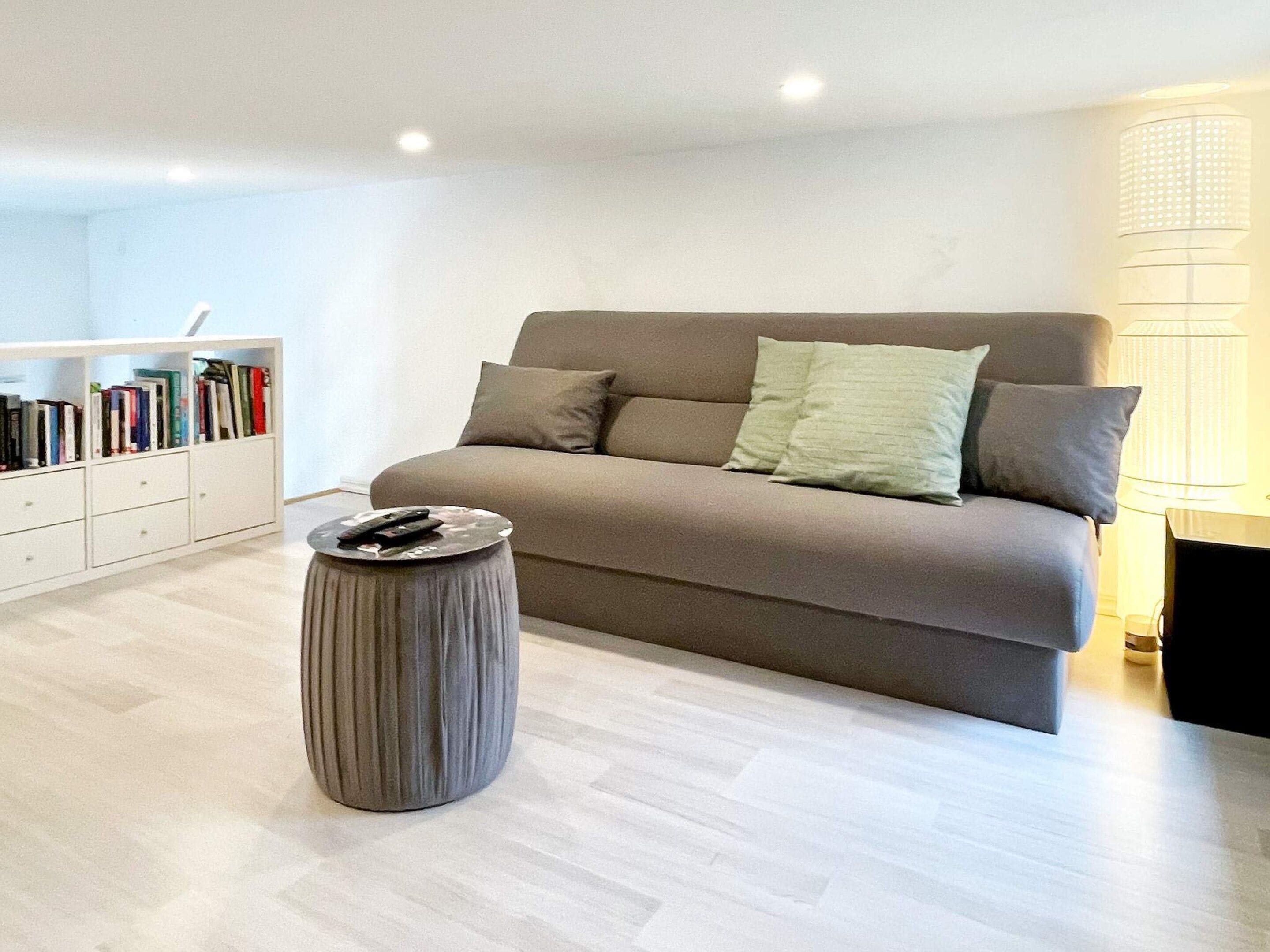 A modern living room with a sofa, a side table, and a bookshelf.