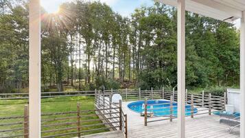 A wooden deck with a pool, surrounded by a wooden fence and trees.