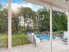 A wooden deck with a pool, surrounded by a wooden fence and trees.