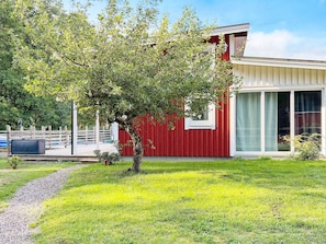 Ein modernes Haus mit rotem Anstrich, ein Baum im Vorgarten und ein klarer Himmel.
