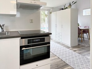 Eine moderne Küche mit Einbauofen, Edelstahl-Dunstabzugshaube und einem weißen Schrank mit Griff.