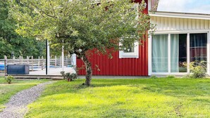 A modern house with a red exterior, a tree in the front yard, and a clear sky. - 4 Star Holiday Home in Rockneby (Rockneby)