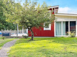 Ein modernes Haus mit rotem Anstrich, ein Baum im Vorgarten und ein klarer Himmel.