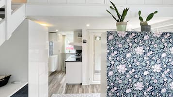 Een moderne keuken met witte kastjes, een decoratieve achterwand en een kleine plant in een pot op het aanrecht.