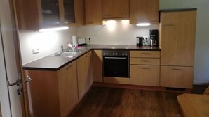 A compact kitchen with wooden cabinets, a dishwasher, and a coffee maker.
