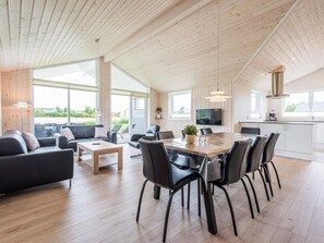 Ein geräumiger Wohnbereich mit Holzboden, einem Esstisch mit Stühlen, einer Couch und einem Fernseher.