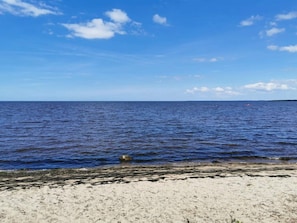 A beach with clear blue water and a sandy shore.