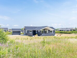 A row of modern, single-story houses with flat roofs, surrounded by a grassy field with wildflowers. - 5 Star Holiday Home in Tarm (Tarm)