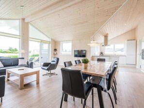 Ein geräumiger Wohnbereich mit Holzboden, einem großen Esstisch und einer Couch.
