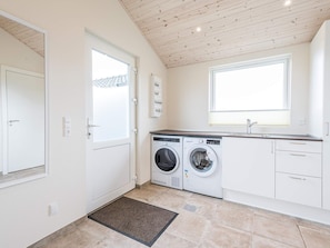 A laundry room with two washing machines, a sink, and a window.