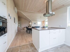 A modern kitchen with a central island, wooden ceiling, and built-in cabinetry.