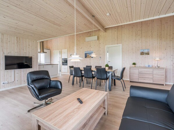 A modern living space with a wooden interior, a dining area, and a seating area.