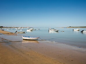 A beach with several boats anchored in calm waters. - Belvilla by OYO Beachfront Apartment (Sanlucar de Barrameda)
