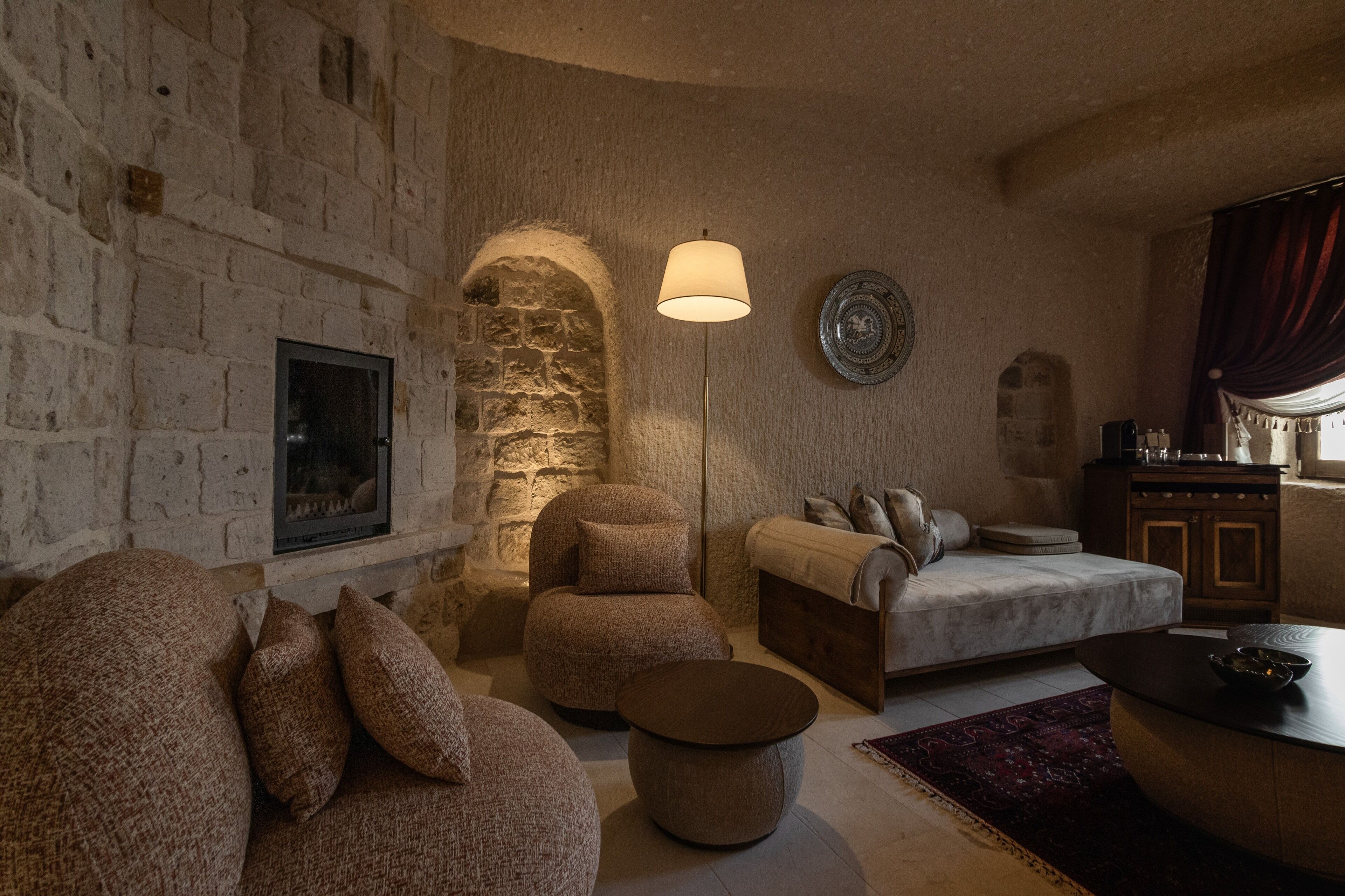 A cozy room with a stone wall, a round table, a sofa, and a bed.