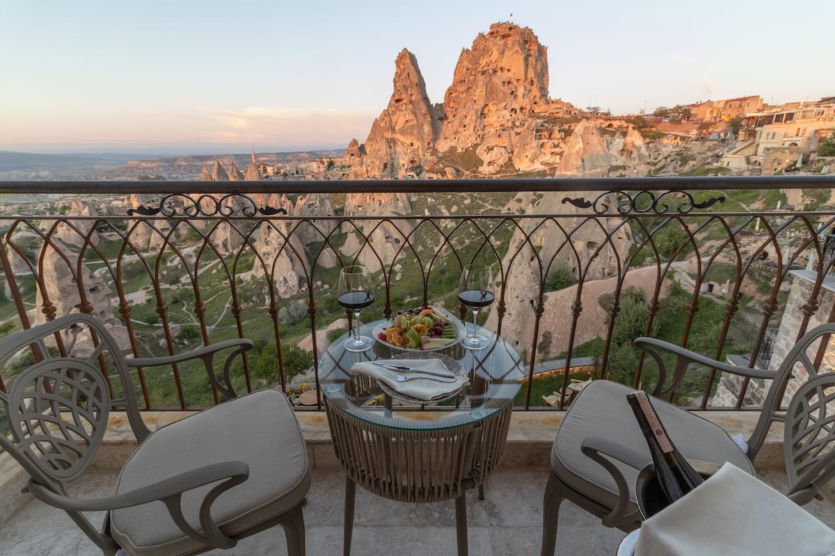A balcony with a table set for two, overlooking a rocky landscape with distinctive rock formations.