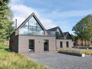 Une maison moderne à deux étages, dotée de grandes fenêtres et d’un toit en pente.