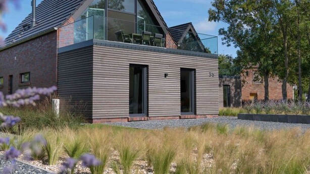 A modern house with a sloped roof, large windows, and a brick facade. - Harlepadd 3c Modern Retreat (Wittmund)