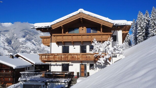 Un bâtiment de style chalet, avec une façade en bois, de grandes fenêtres et un balcon.