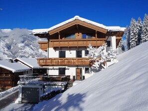 Un edificio in stile chalet con facciata in legno, ampie finestre e un balcone.
