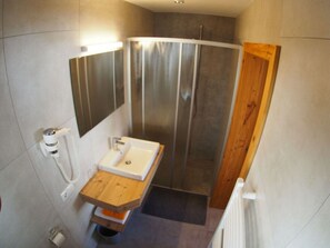A modern bathroom with a wooden vanity, a built-in sink, and a shower enclosure. - Vakantiehuis Sonneck (Hainzenberg)