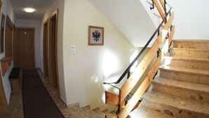 Un escalier avec des marches en bois et des rampes en métal, menant à l’étage supérieur.