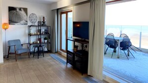 A modern living room with a TV, bookshelf, and seating area. - Attic Apartment Nieuwpoort With Coastal Views (Nieuwpoort)