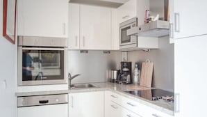 Eine moderne Küche mit weißen Schränken, einem Backofen, einer Mikrowelle und einer Kaffeemaschine.