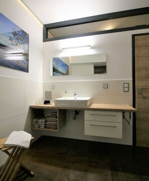 A modern bathroom with a white sink, a mirror above it, and a towel rack to the left. - Apartment in Eibenstock (Eibenstock)