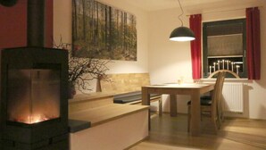A cozy room with a fireplace, a dining table, and a bench. - Apartment in Eibenstock (Eibenstock)