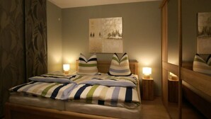 A bedroom with a bed, two bedside tables with lamps, a large mirror, and a painting on the wall. - Apartment in Eibenstock (Eibenstock)