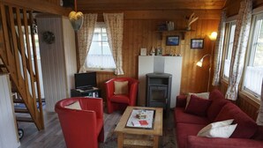 En hyggelig stue med en rød sofa, en rød lænestol, et træbord og en pejs.