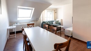 A compact, modern apartment with a dining area, a sofa, and a small table. - Villa Modern Duplex Apartment (De Haan)