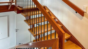 Un escalier en bois, doté d’une rampe et d’une porte en bas.