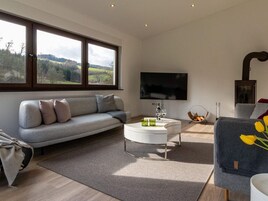 A modern living room with a grey sofa, a white coffee table, a flat-screen TV, and a fireplace.