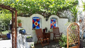 Una zona patio con due sedie di legno, un tavolino e un fioriera in legno.