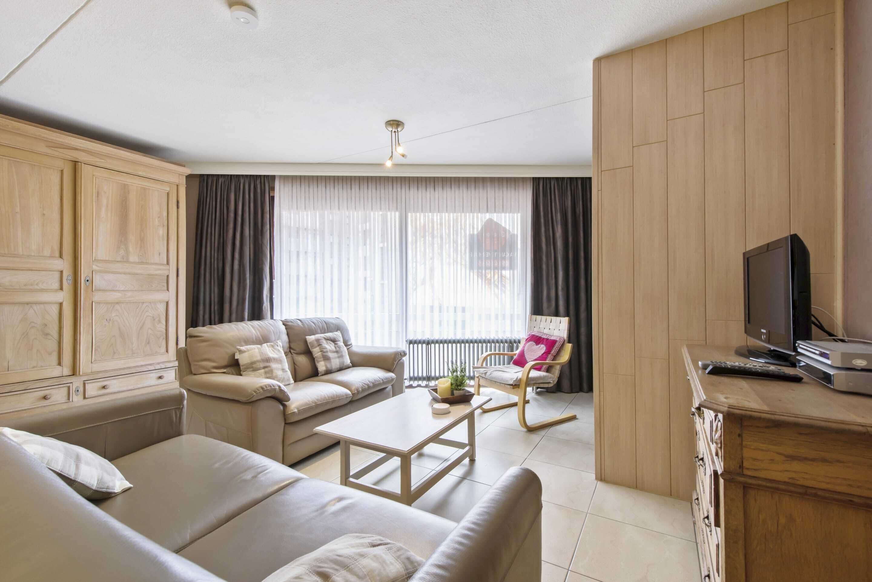 Una sala de estar con sofá, mesa de centro, televisor y una silla.